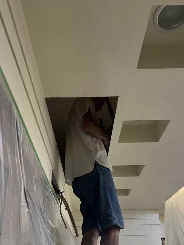 師傅由天花板開孔進入，整理天花板內的管線路徑