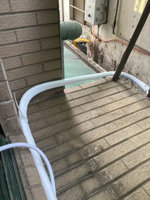 室外平台上的新管線沿牆角佈設，保溫管全段包覆
