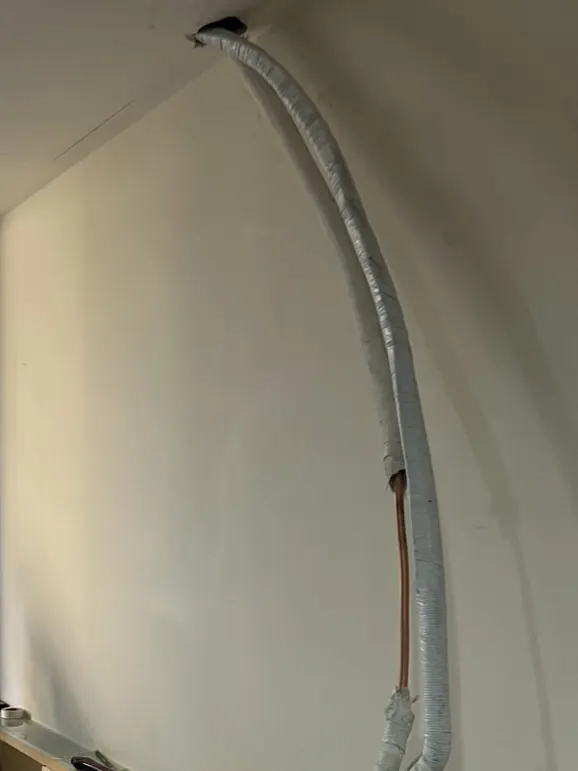 施工中：新管線沿牆面配置，地面與床頭櫃旁放置施工工具